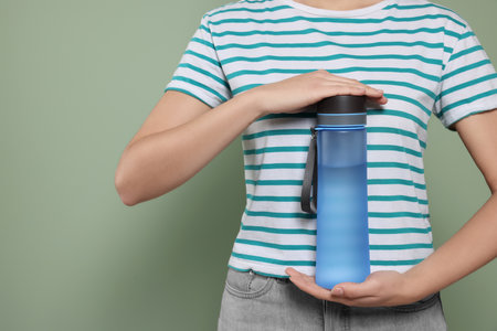 Woman holding bottle of water on green background, closeup. Space for textの写真素材