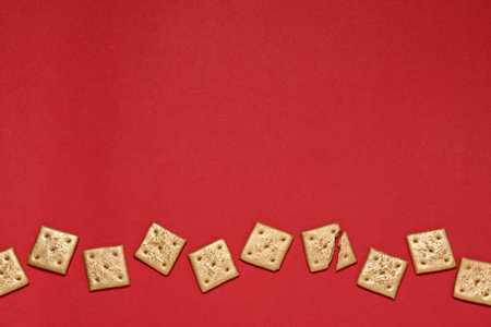 Golden cookies on red background, flat lay. Space for textの写真素材