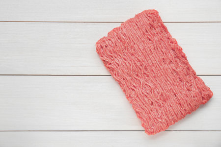 Raw fresh minced meat on white wooden table, top view. Space for text