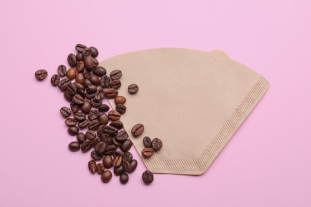 Paper coffee filter and beans on pale pink background, flat layの写真素材