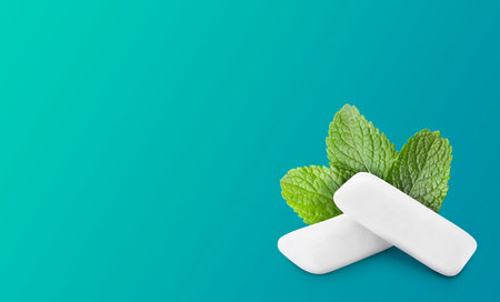 Menthol chewing gum pillows and mint leaves on blue gradient background, space for text