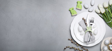 Festive Easter table setting with tulips and painted eggs on light gray background, flat lay. Banner design with space for textの写真素材