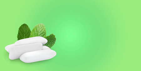 Menthol chewing gum pillows and mint leaves on light green gradient background, space for text....