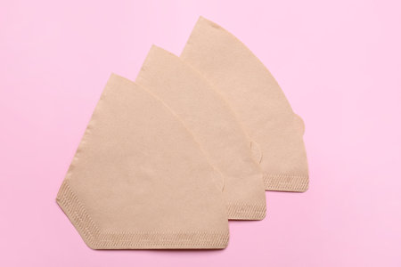 Paper coffee filters on pale pink background, flat layの写真素材