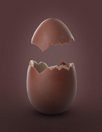 Broken milk chocolate egg on brown background