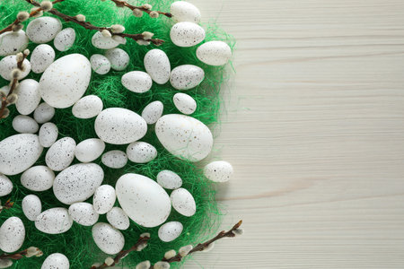 Many beautifully painted Easter eggs and pussy willow branches on white wooden table, flat lay....