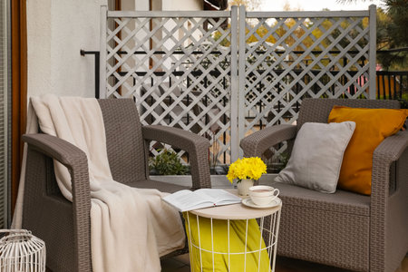 Different pillows, book and beautiful chrysanthemum flowers on garden furniture outdoorsの写真素材