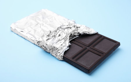 One tasty chocolate bar on light blue background