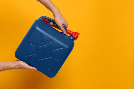 Man holding blue canister on orange background, closeup. Space for textの写真素材