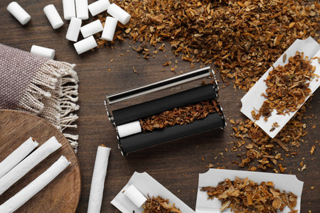 Flat lay composition with roller and tobacco on wooden table. Making hand rolled cigarettesの写真素材