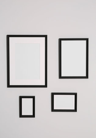 Different empty frames hanging on white wallの写真素材