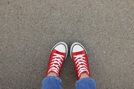 Woman in stylish gumshoes on asphalt, top viewの写真素材