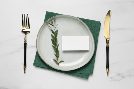 Stylish setting with cutlery, eucalyptus leaves and blank card on white marble table, flat lay. Space for textの写真素材