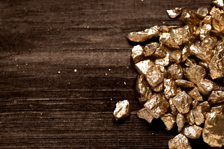 Pile of shiny gold nuggets on wooden table, flat lay. Space for text