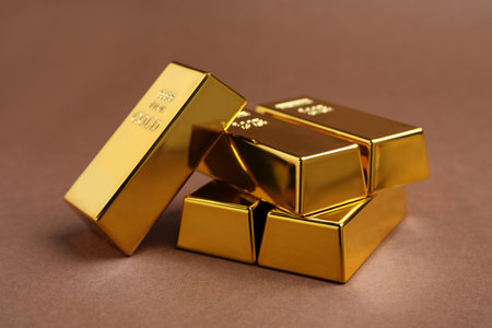 Many shiny gold bars on brown background