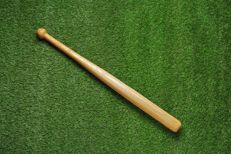 Wooden baseball bat on green grass, top view. sports equipmentの写真素材