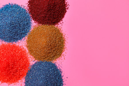 Heaps of different bright food coloring on pink background, flat lay. Space for textの写真素材