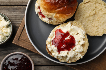 Freshly baked soda water scones with cranberry jam and butter on wooden table, flat layの写真素材