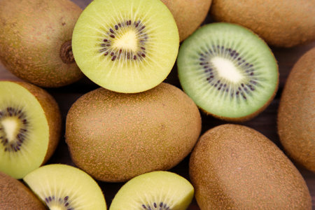 whole Many and cut fresh kiwis on wooden table, closeupの写真素材