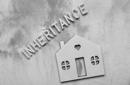 Word Inheritance made with white letters and model house on grey background, flat layの写真素材
