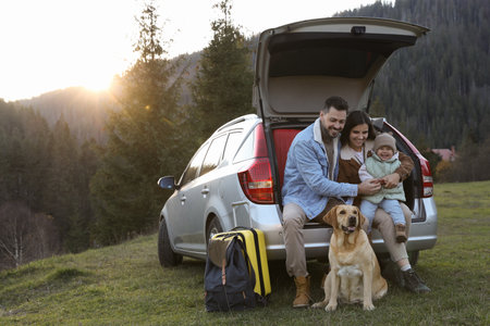 Parents, their daughter and dog near car in mountains, space for text. Family traveling with petの写真素材