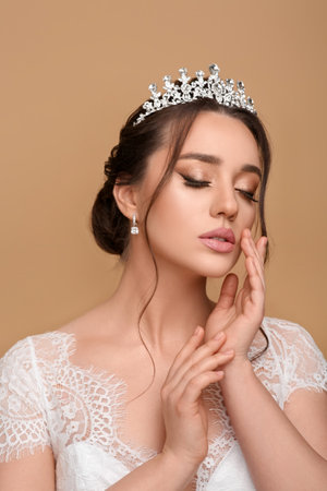 Beautiful young woman wearing luxurious tiara on beige backgroundの写真素材