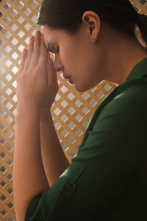 Woman praying to God during confession in boothの写真素材