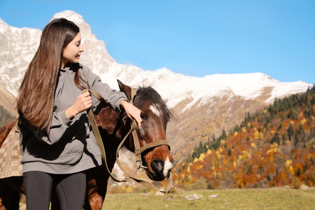 Young woman with horse in mountains on sunny day, space for text. beautiful petの写真素材
