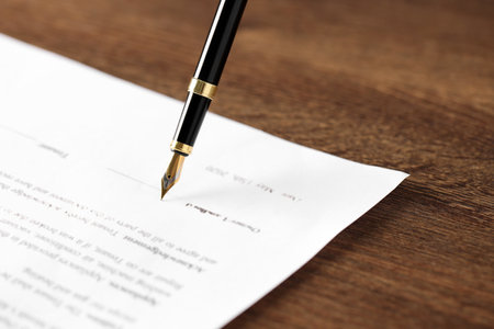 Writing on document with fountain pen at wooden table, closeup. Notary contractの写真素材