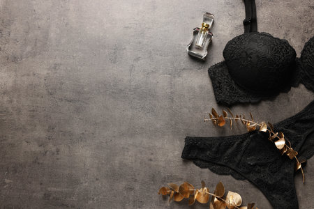 Elegant black women's underwear, perfume and decorative golden branches on gray textured background, flat lay. Space for textの写真素材