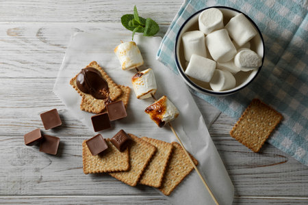 Ingredients for delicious sandwich with roasted marshmallows and chocolate on white wooden table,...