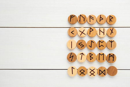 Runes with different symbols on white wooden table, flat lay. Space for text