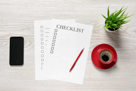 Paper sheet with inscription Checklist, cup of coffee, smartphone and plant on white wooden table, flat layの写真素材