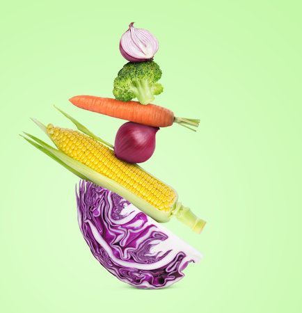 Stack of different fresh vegetables on light green backgroundの写真素材