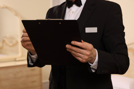 Man in suit with clipboard indoors, closeup. Professional butler coursesの写真素材