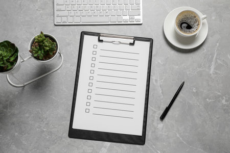 Clipboard with checkboxes, cup of coffee, plants and computer keyboard on light gray table, flat lay. Checklistの写真素材