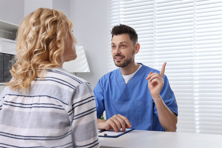 Doctor with clipboard consulting patient in clinicの写真素材