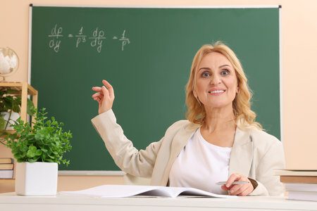 Professor pointing at green board with math equation in classroomの写真素材