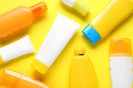 Suntan products on yellow background, flat lay