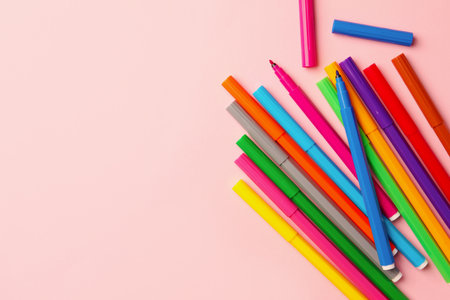 Many bright markers on pink background, flat lay. Space for text