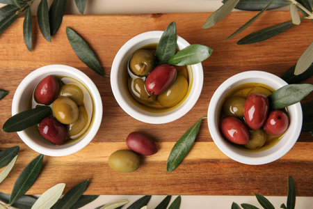 Bowls with different ripe olives and leaves on beige background, flat layの写真素材