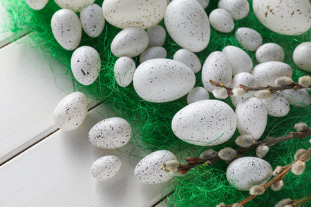 Many beautifully painted Easter eggs and pussy willow branches on white wooden tableの写真素材