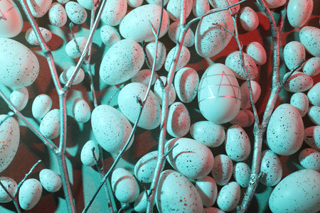 Many painted Easter eggs and tree twigs in blue neon light, flat lay