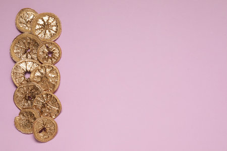 Golden lemon slices on pink background, flat lay. Space for text