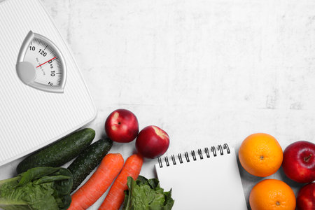 Scales, notebook, fresh fruits and vegetables on light gray textured table, flat lay with space for text. Low glycemic index dietの写真素材