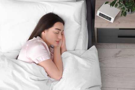 Beautiful young woman sleeping in soft bed at home, top viewの写真素材