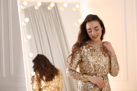 Beautiful woman in elegant dress near mirror indoors, space for text