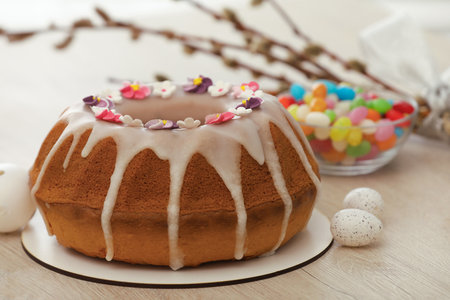 Delicious Easter cake decorated with sprinkles near eggs and candies on white wooden table, closeupの写真素材