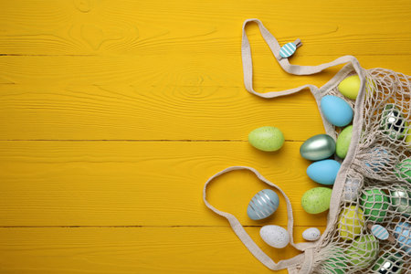 Many beautifully decorated Easter eggs on yellow wooden table, flat lay. Space for textの写真素材