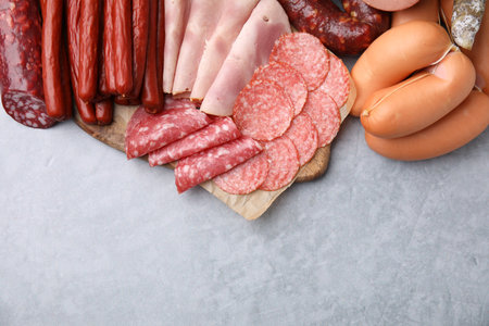 Different types of sausages on light gray table, flat lay. Space for text